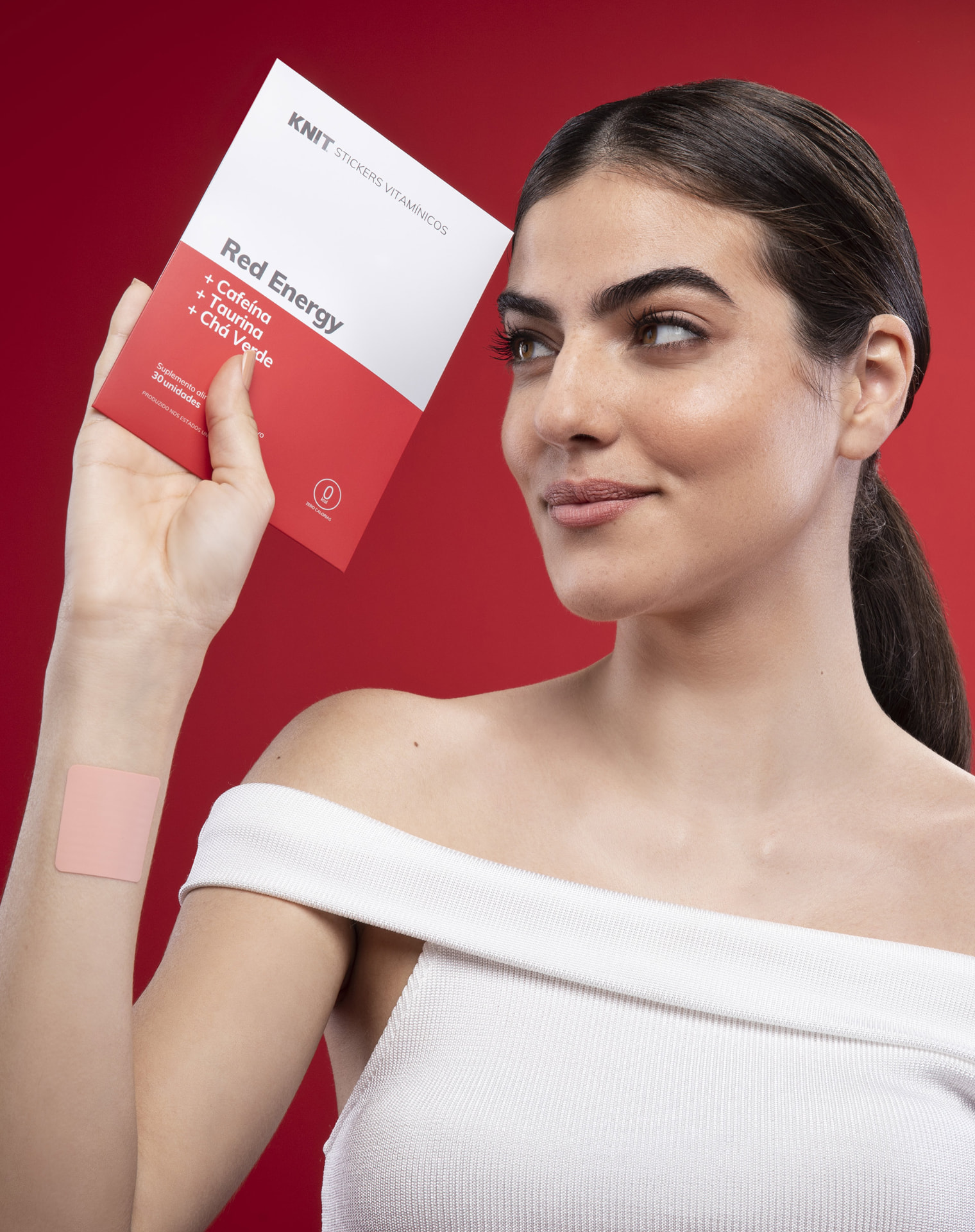 Model holding a Red Energy KNIT vitamin patch pack with a patch applied to the arm
