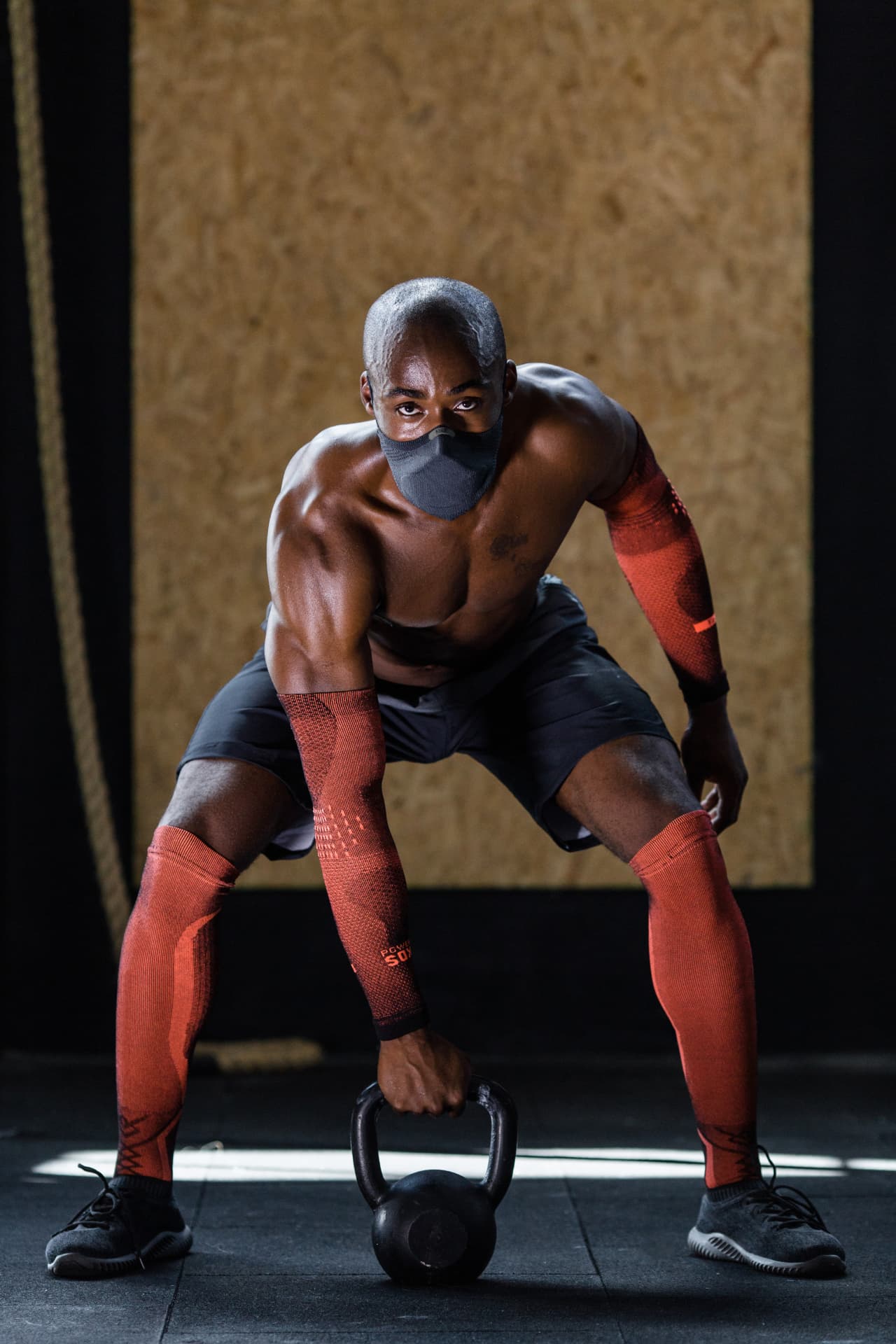 Athlete wearing red KNIT compression arm sleeves while lifting a kettlebell